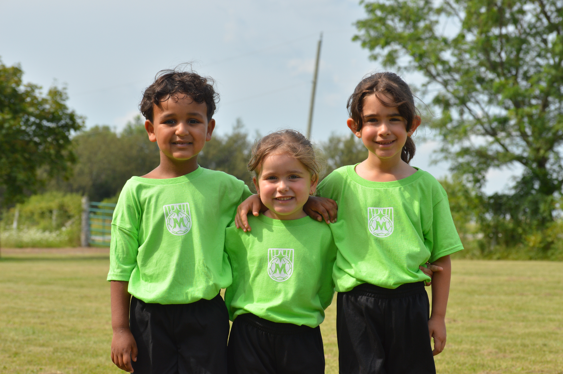 Three young Maravilha Mini's players smiling in green jerseys