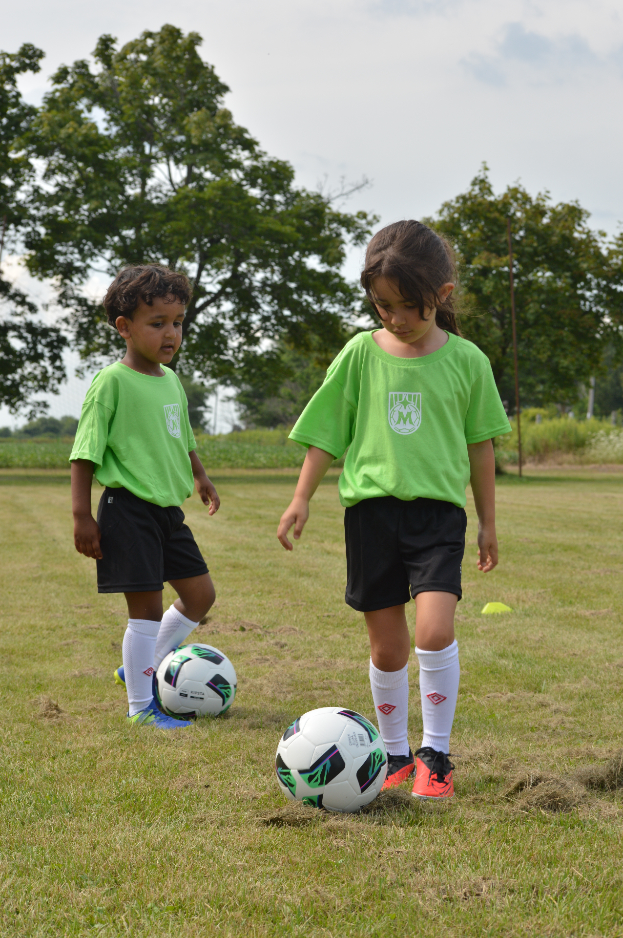Two Maravilha Mini's players dribbling soccer balls