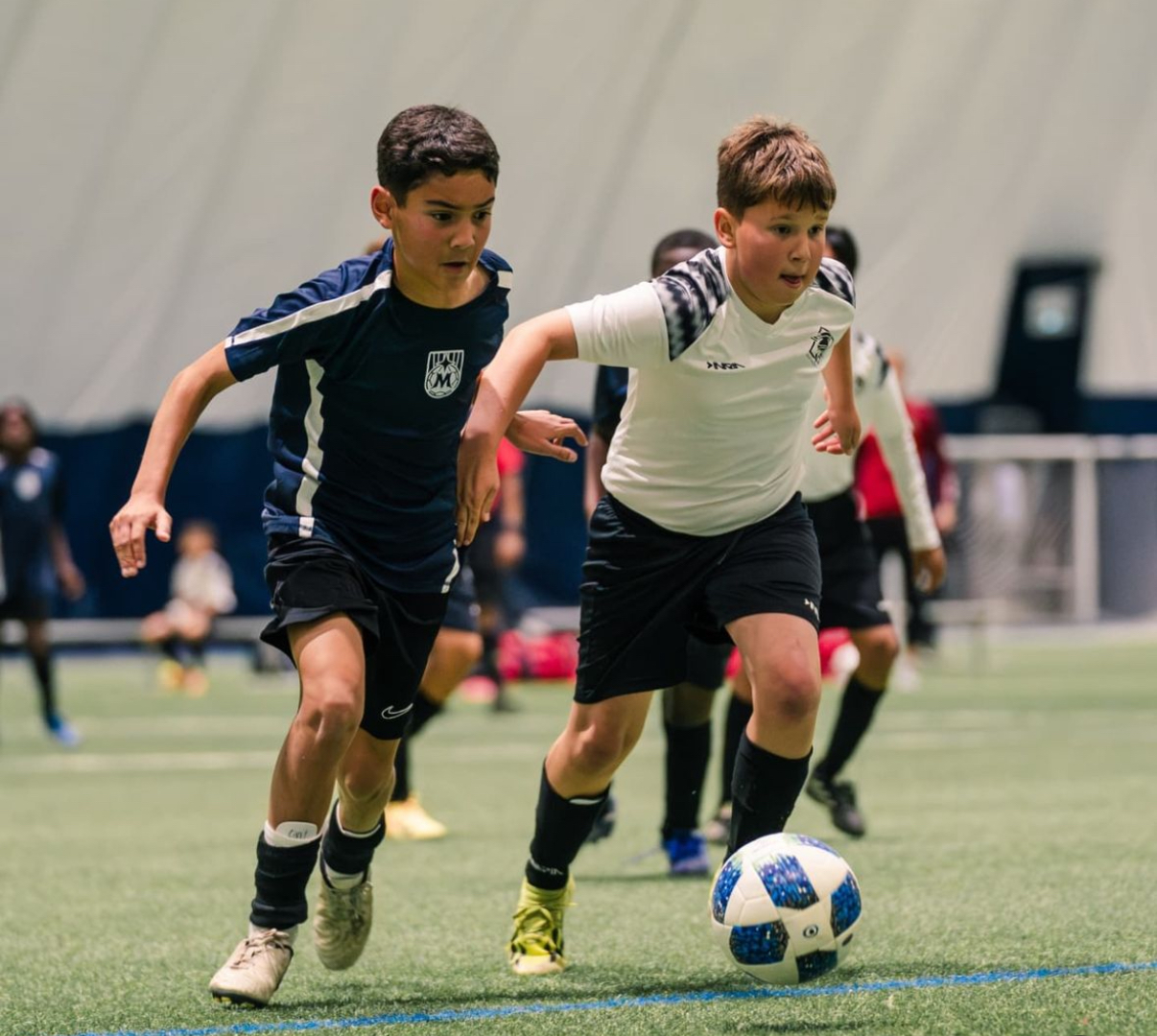 Competitive rep players racing for the ball during indoor play